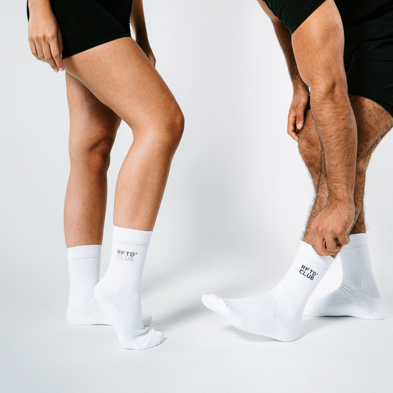 Eine Frau und ein mann zeigen in Sportklamotten die Socken die sie tragen und setzen diese in Szene. Zu sehen ist jeweils der Unterkörper.