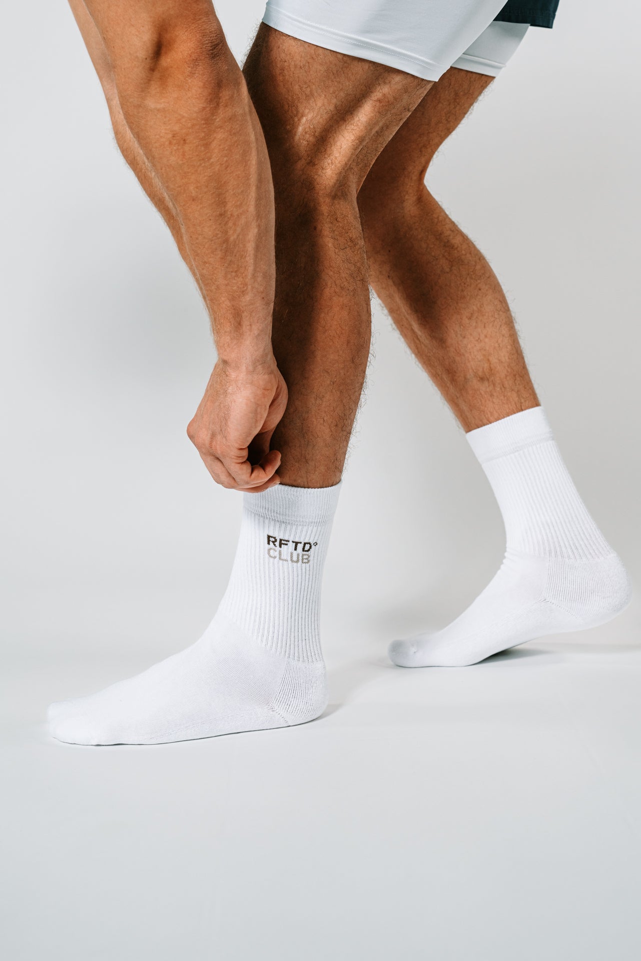 Mann bückt sich und zieht sich die RFTD Socke an