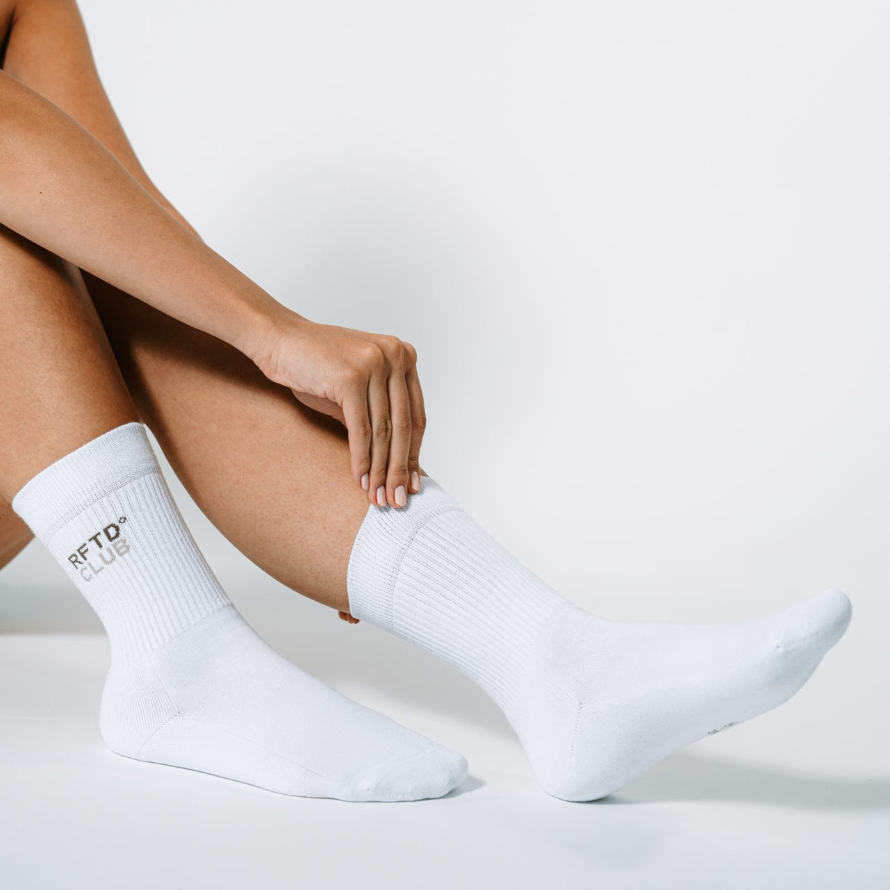 Zu sehen sind die Füße einer Frau und sie trägt die RFTD Sportsocken. Sie richtet sich die Socke mit der Hand.